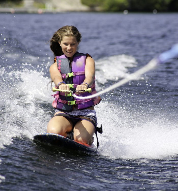 A teenage girl enjoying her first try on a kneeboard. She is on a lake in Muskoka, Ontario, Ontario, Canada